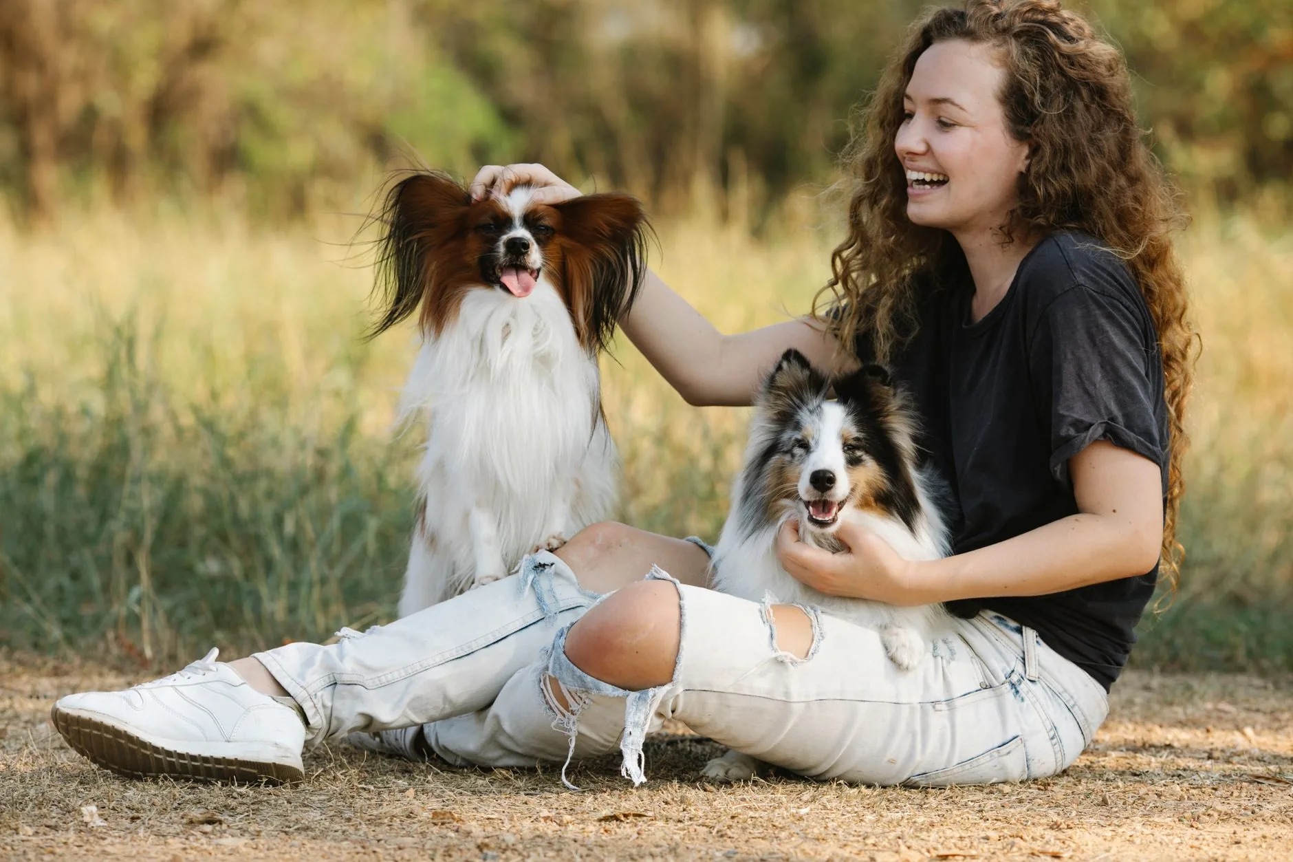 A smiling woman outdoors with her two dogs